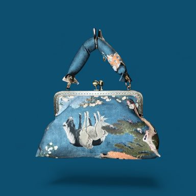 Monedero de tela con estampado colorido y asas de tela. Fondo azul.
