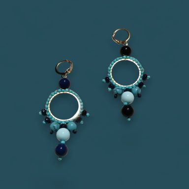 Pendientes con aro dorado y cuentas de colores en azul y negro.