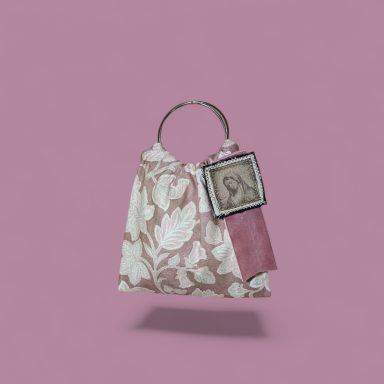 Bolso con diseño floral en tonos rosa y un retrato en una etiqueta. Fondo rosa.